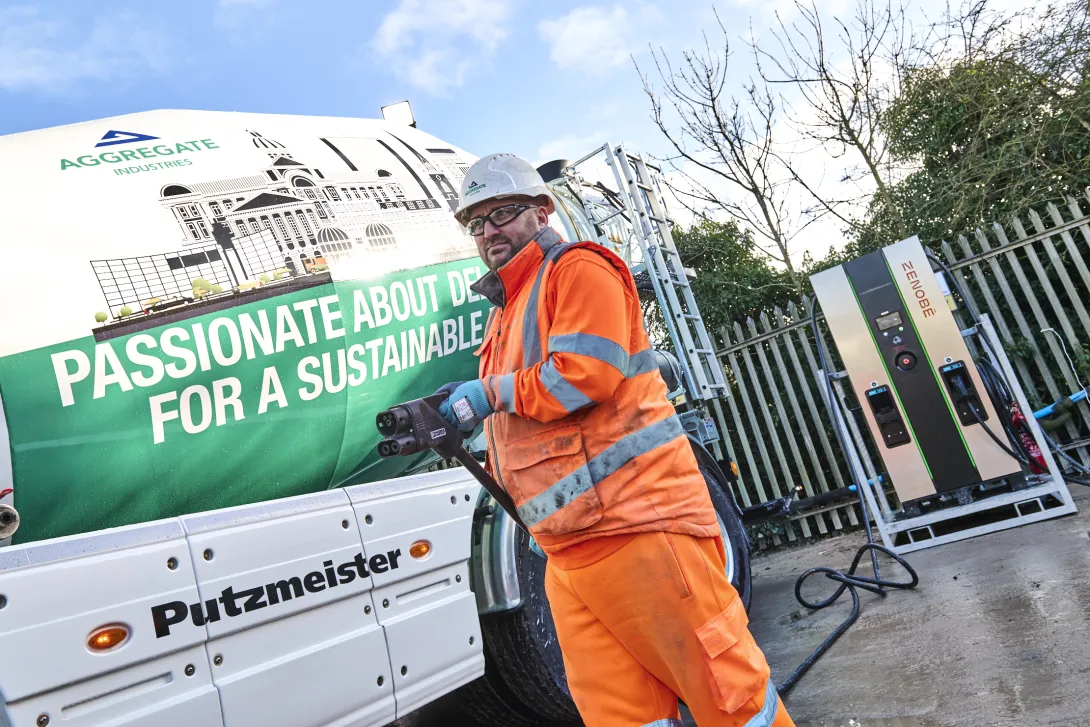 The new Sany Putzmeister emixer truck at Coleshill Readymix plant with the driver holding the EV charging wand