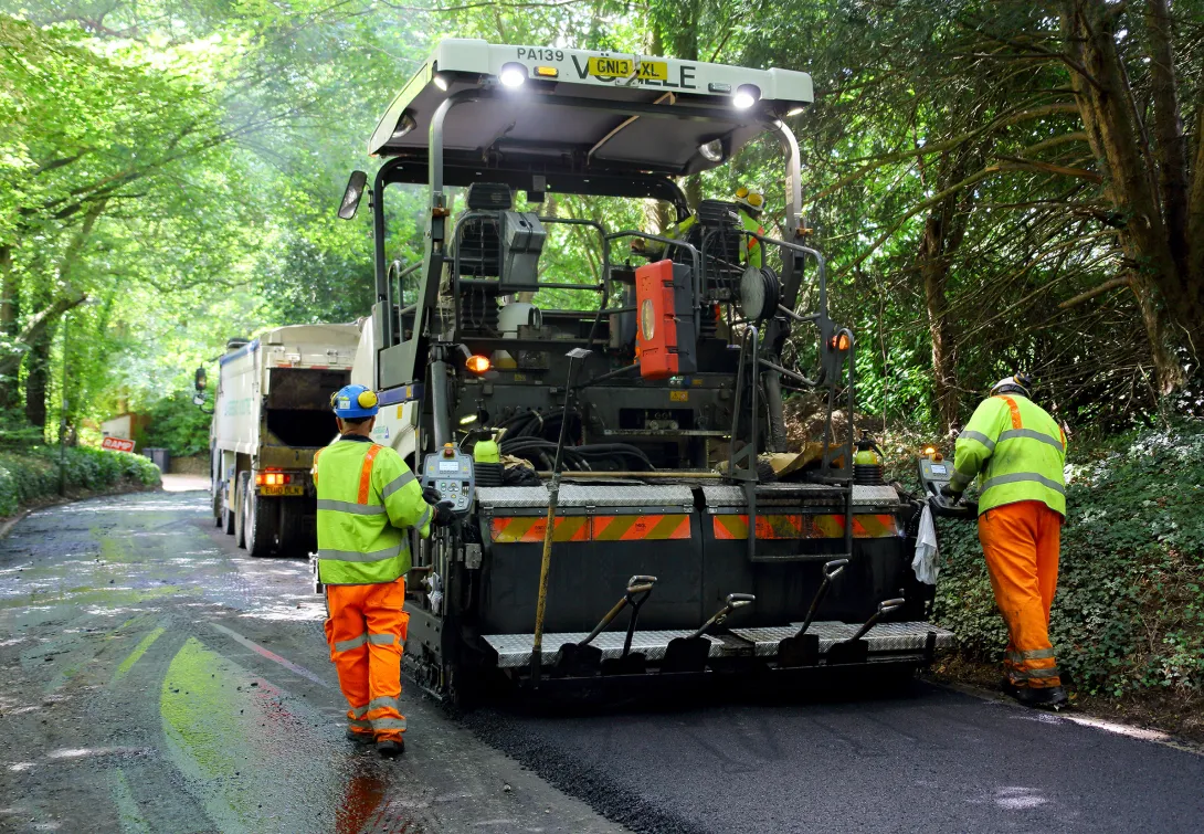 Workers spreading asphalt onto a forest road