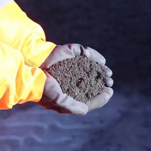 Person in high-vis holding Aggregate Sand form Aggregate Industries
